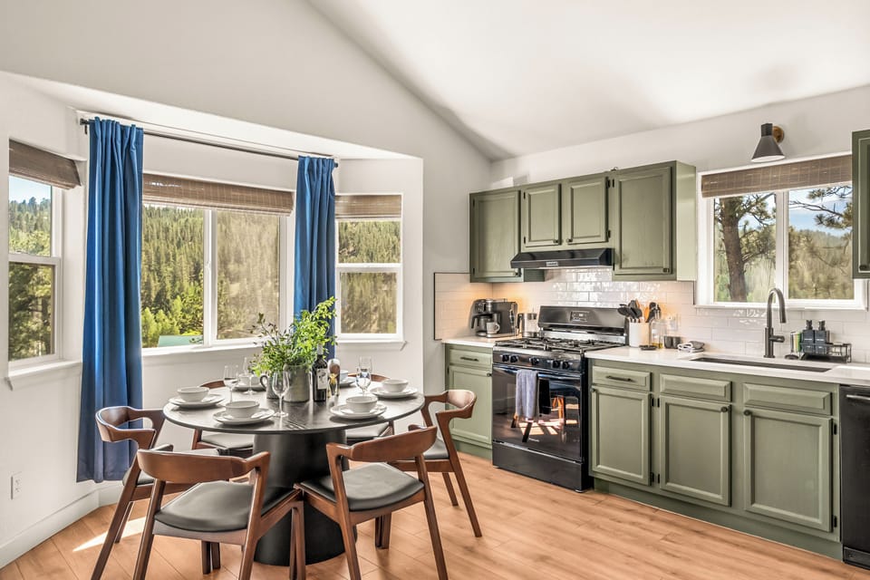 Bright mountain-view kitchen with dining for four and stylish sage cabinetry