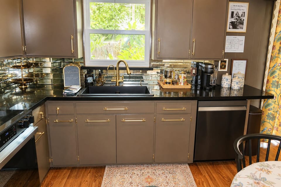 Bright designer kitchen with brass accents, coffee station, and garden views