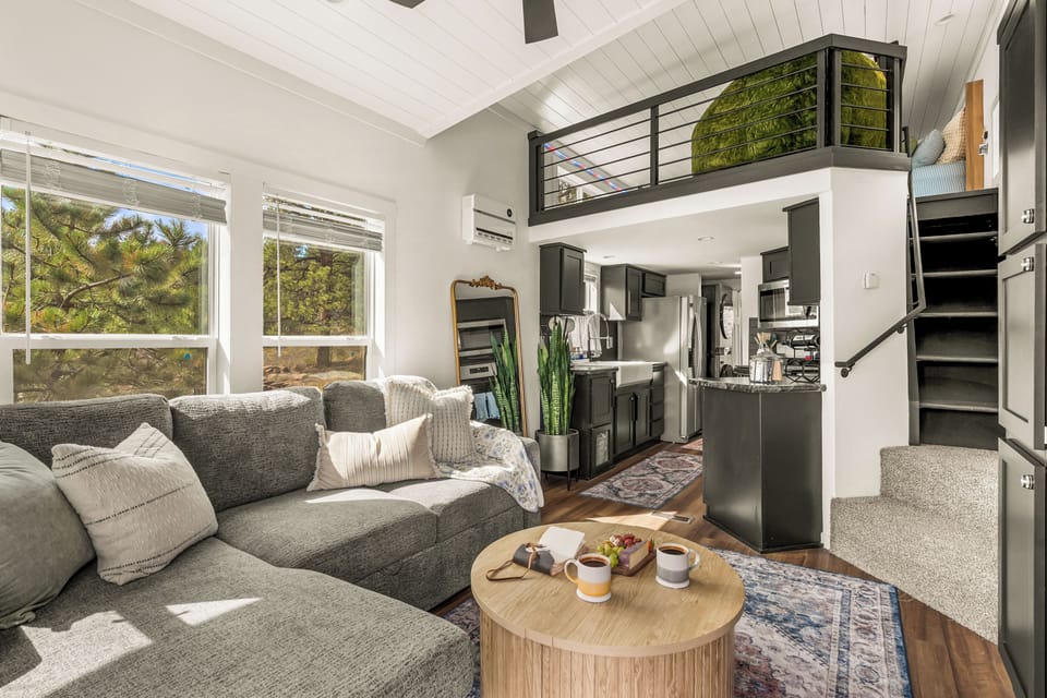 Sink into the sectional and take in the whole layout at a glance — kitchen behind you, the loft tucked up top, stairs leading to even more space.
