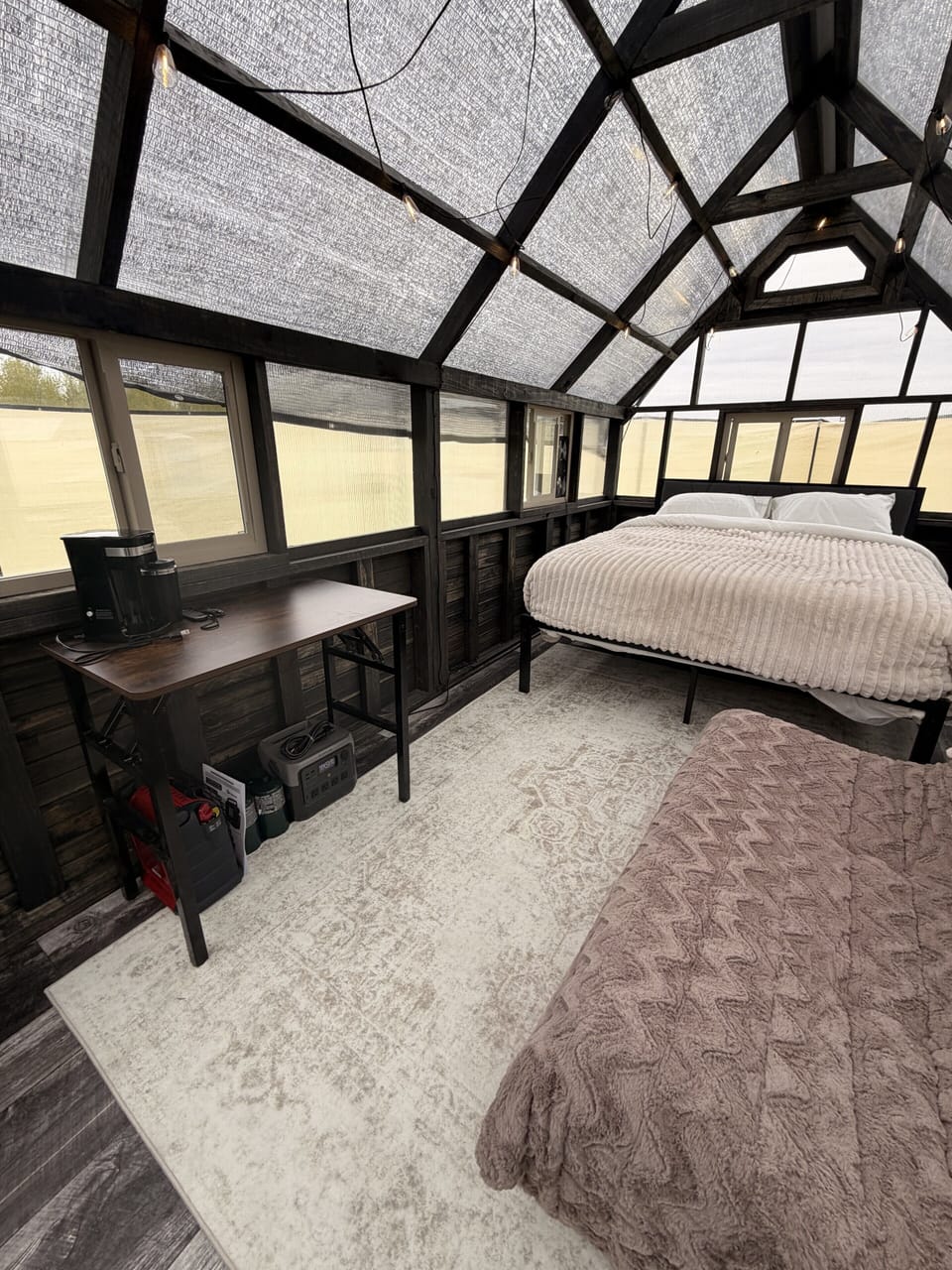 Unique glass-roof sleeping nook with cozy bed and bright, airy vibes