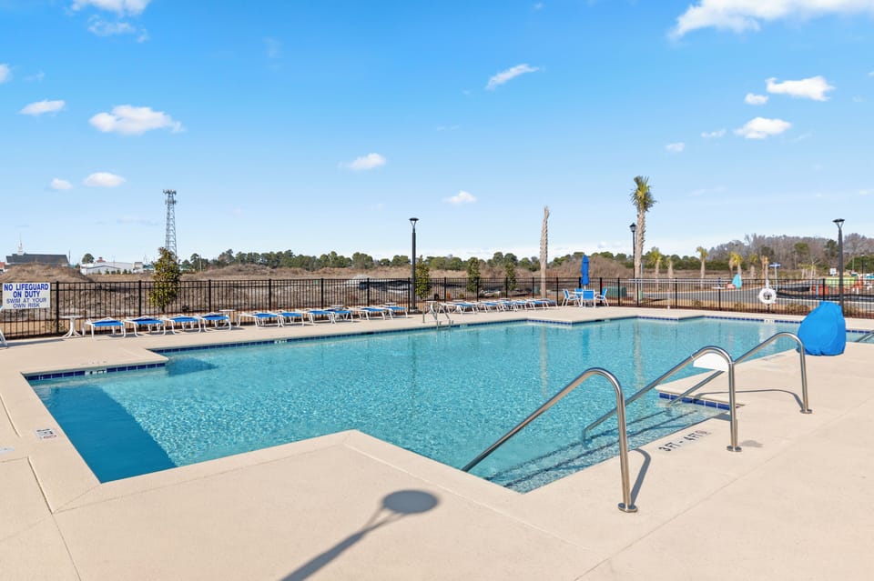 Pristine community swimming pool area under a clear blue sky.