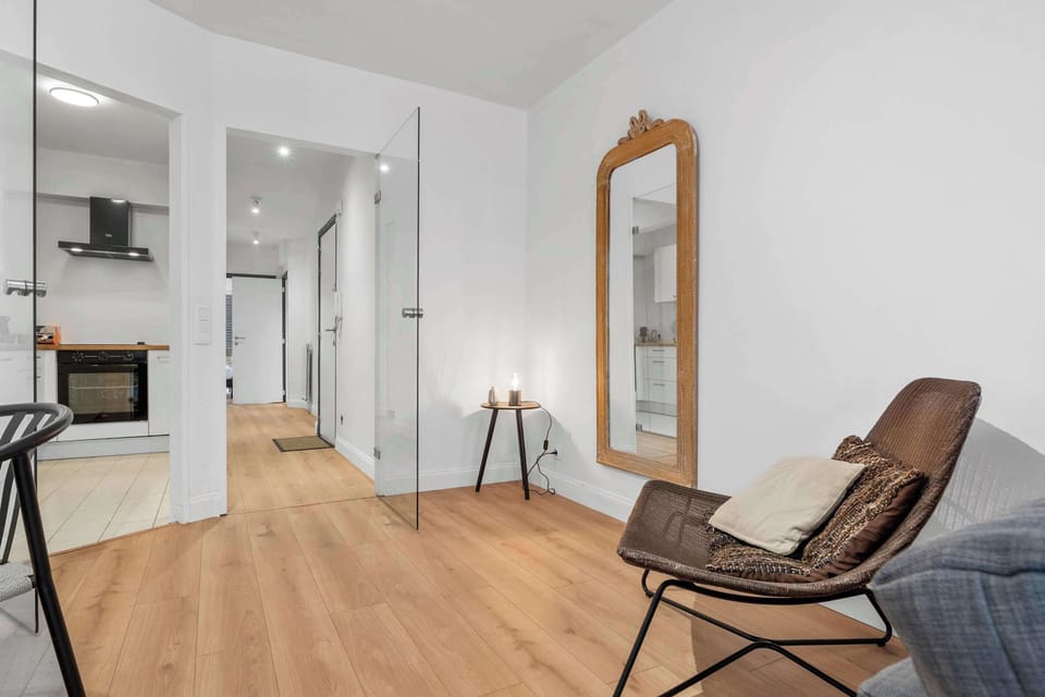 Bright, airy living space with a cosy armchair and tasteful décor, flowing through this clean, contemporary 1-bedroom Knokke holiday apartment.