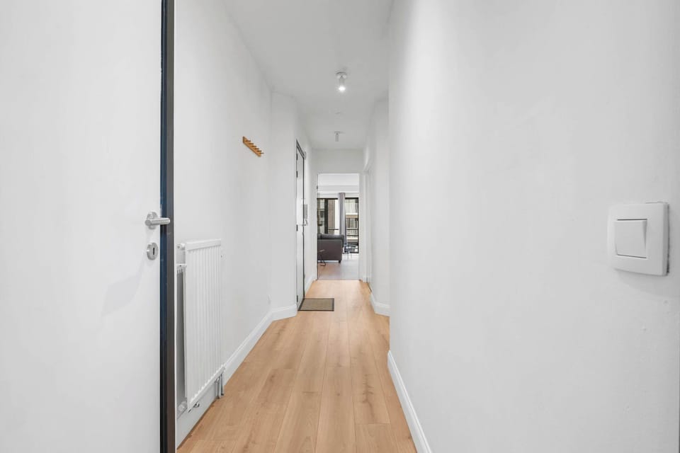 Bright hallway with warm wood flooring connecting the rooms of this clean, contemporary apartment near the beach in Knokke.