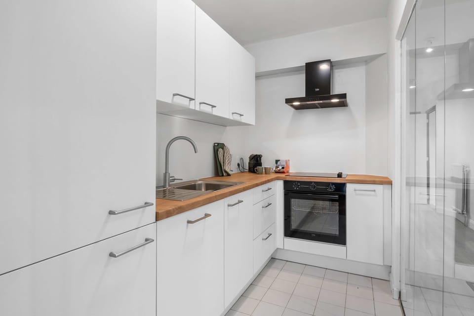 Fully equipped modern kitchen with sleek cabinetry, an oven and range hood, ready for home-cooked meals in this stylish central Knokke apartment.