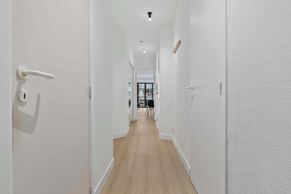 Bright hallway with warm wood flooring linking the rooms of this clean, contemporary 2-bedroom apartment near the beach in Knokke.