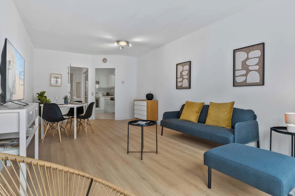 Open living and dining area with a vibrant blue sofa and golden cushions, offering a warm, sociable space in this stylish 2-bedroom Knokke apartment.