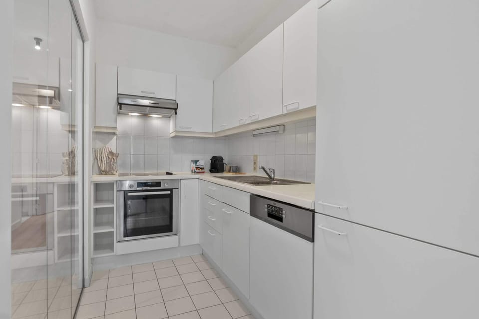 Fully equipped modern kitchen with sleek white cabinetry and an oven, ready for home-cooked meals during your stay in this Knokke holiday apartment.