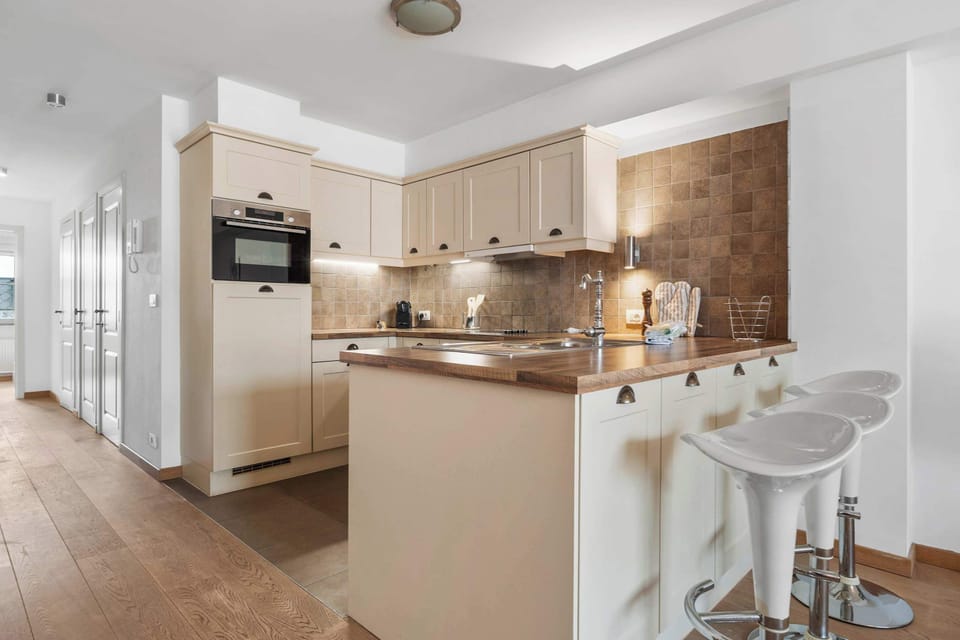 Kitchen breakfast bar with stools and ample cabinetry – cook and gather in our Charming Duplex in Knokke.