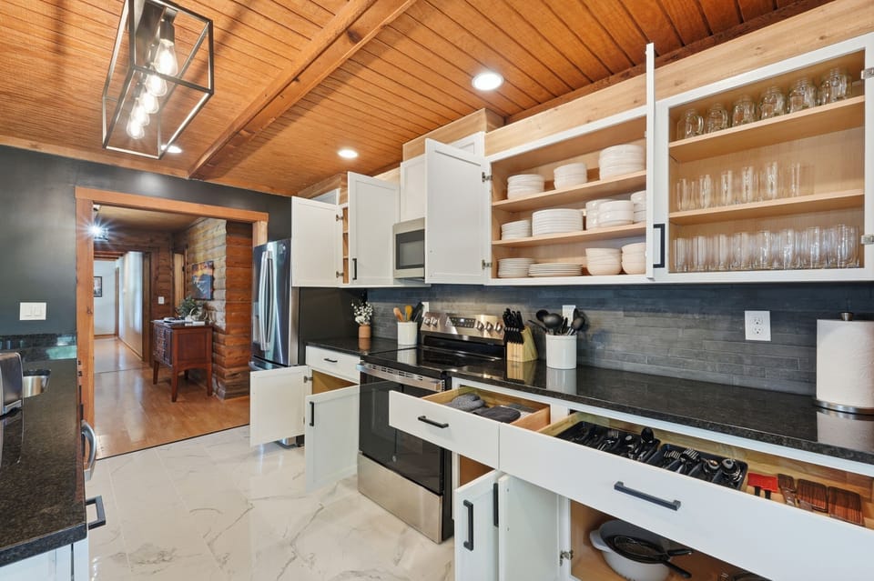 Bright, fully stocked kitchen with warm wood ceilings and modern finishes