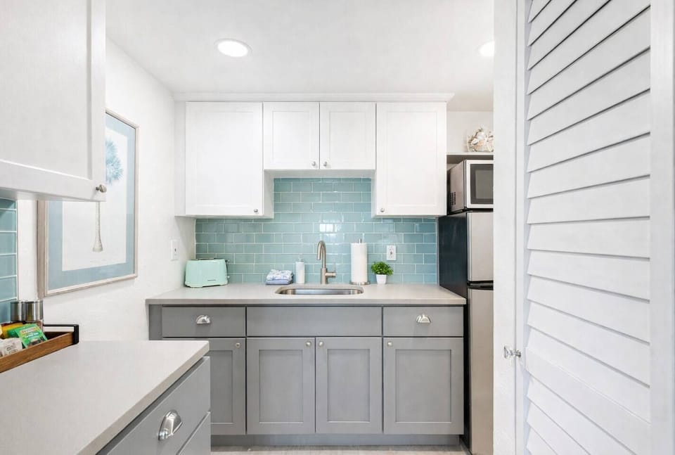 Modern kitchenette with sleek finishes, coastal tile backsplash, and everything you need for quick meals or morning coffee.