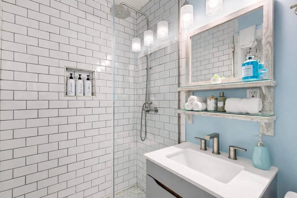Spa-style bathroom with walk-in glass shower, crisp white tile, and fresh coastal touches for a clean, elevated experience.