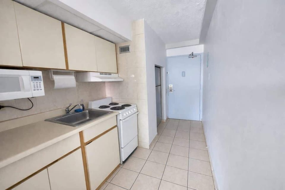 Clean and efficient galley-style kitchen with full-size stove, microwave, and ample cabinet storage. A bright, practical space designed to make meal prep simple and convenient during your stay.