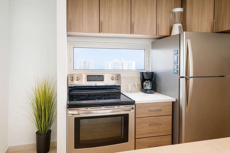 Modern kitchen with stainless steel appliances, sleek wood cabinetry, and bright natural light — perfect for cooking or enjoying your morning coffee.