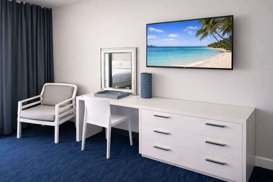 Comfortable studio living space with a seating area, workspace, and TV, all filled with natural light from the private balcony.