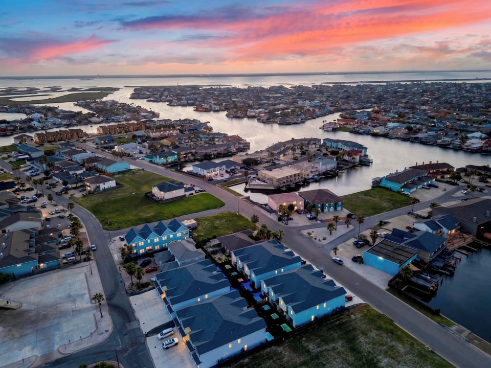 Dramatic sunset aerial view showing the property situated within a vibrant, water-centric coastal community.