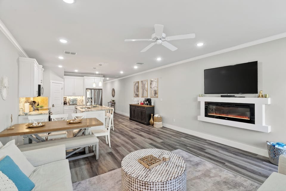 The bright, expansive open-concept living area flows seamlessly, anchored by a modern linear fireplace.