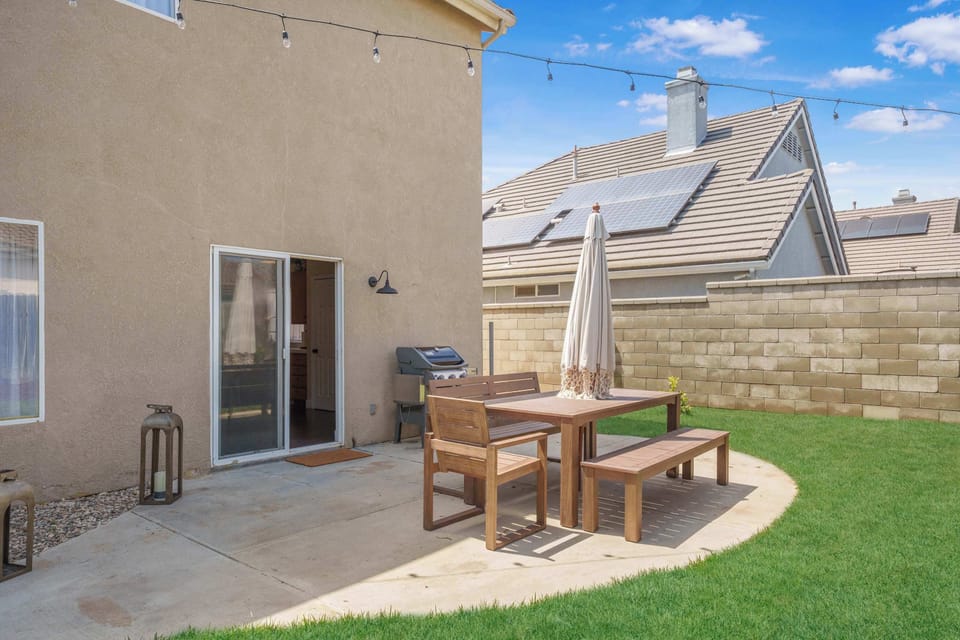 Fully fenced backyard featuring outdoor dining area with umbrella