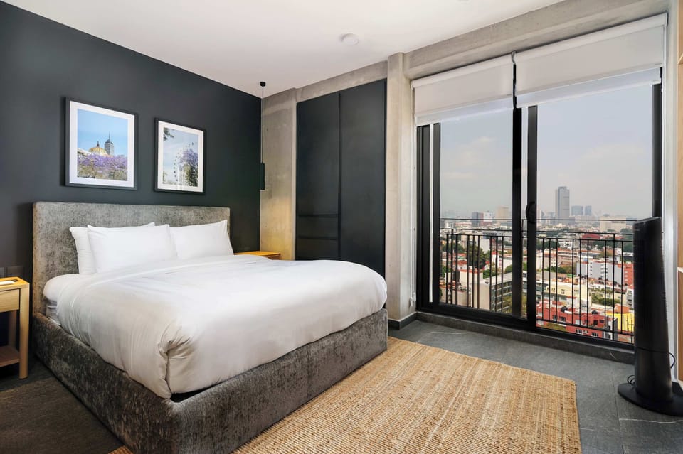 Cozy bed with floor-to-ceiling windows and beautiful city views.