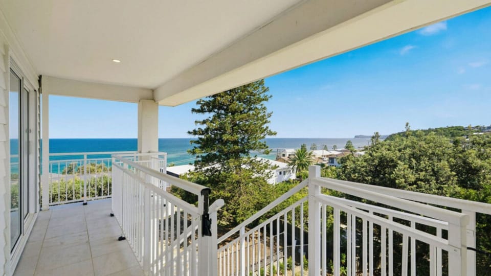 Covered balcony with sweeping ocean and treetop views.