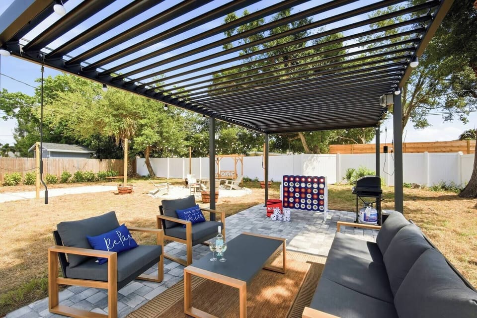 Relax under the covered pergola with comfortable outdoor seating, a BBQ grill, and string lights. The spacious, fenced backyard features giant Connect 4, Yahtzee, a fire pit, and plenty of room for kids and the whole family to enjoy.