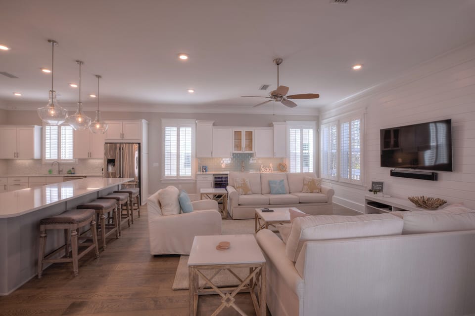 Wide view of the living area showing the ceiling fan and recessed lighting.