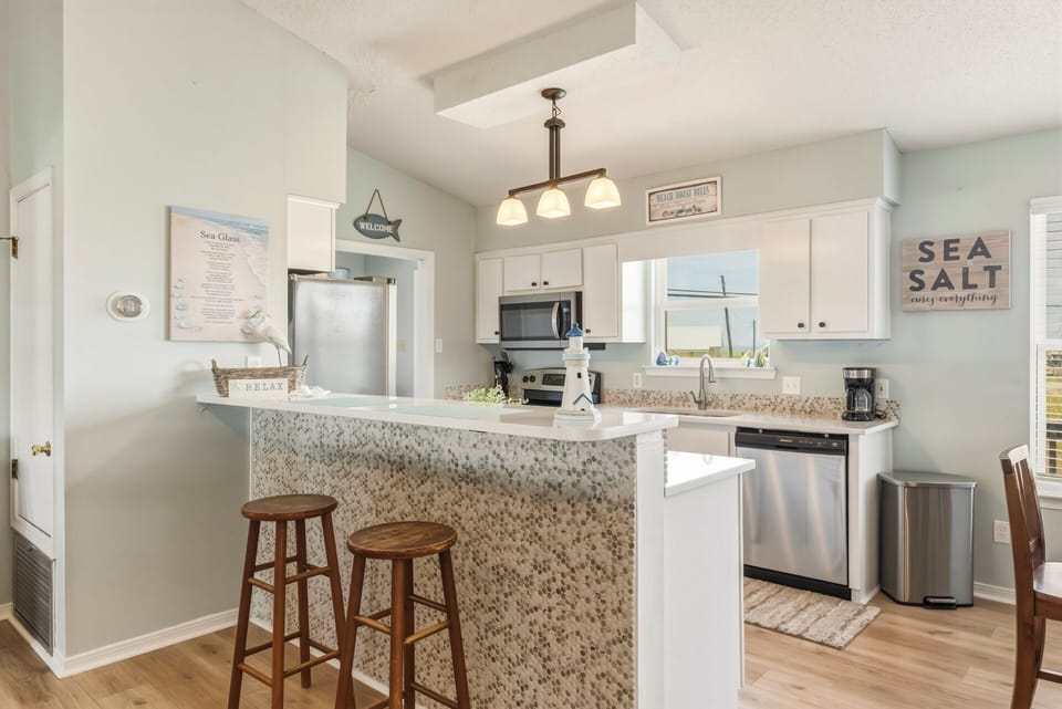 Step into your bright coastal kitchen where quartz countertops and stainless-steel appliances meet beach-inspired charm. Pull up a stool to the breakfast bar and start planning your day's adventures.