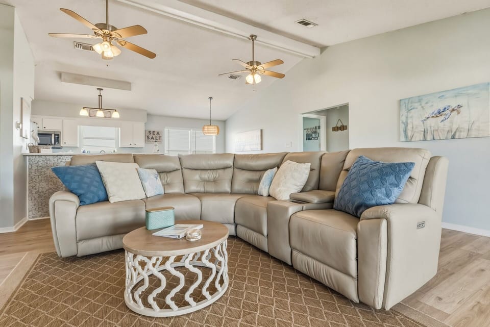 Sink into your spacious sectional and feel the coastal calm of this bright, open living area. With soft neutral tones, breezy ceiling fans, and plenty of room to gather, it's your perfect place to unwind after a beach day.