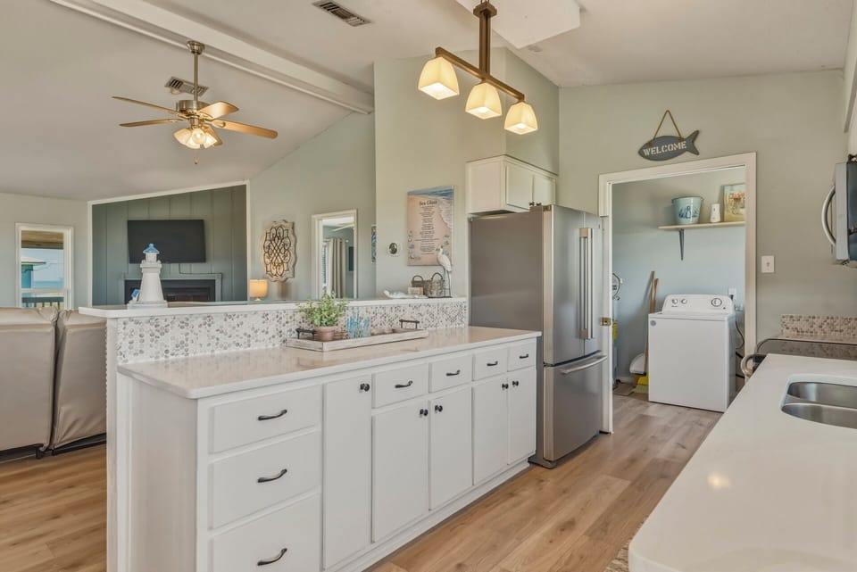 Step into your fully-equipped kitchen featuring a bright open layout, modern appliances, and stylish coastal touches that make meal prep feel like part of your vacation.