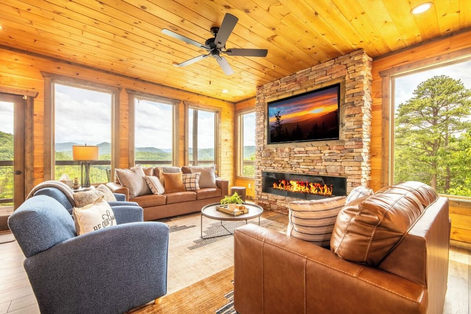 Unwind in your expansive living room where floor-to-ceiling windows frame stunning mountain views, while the stone fireplace and plush seating invite cozy evenings with friends and family.