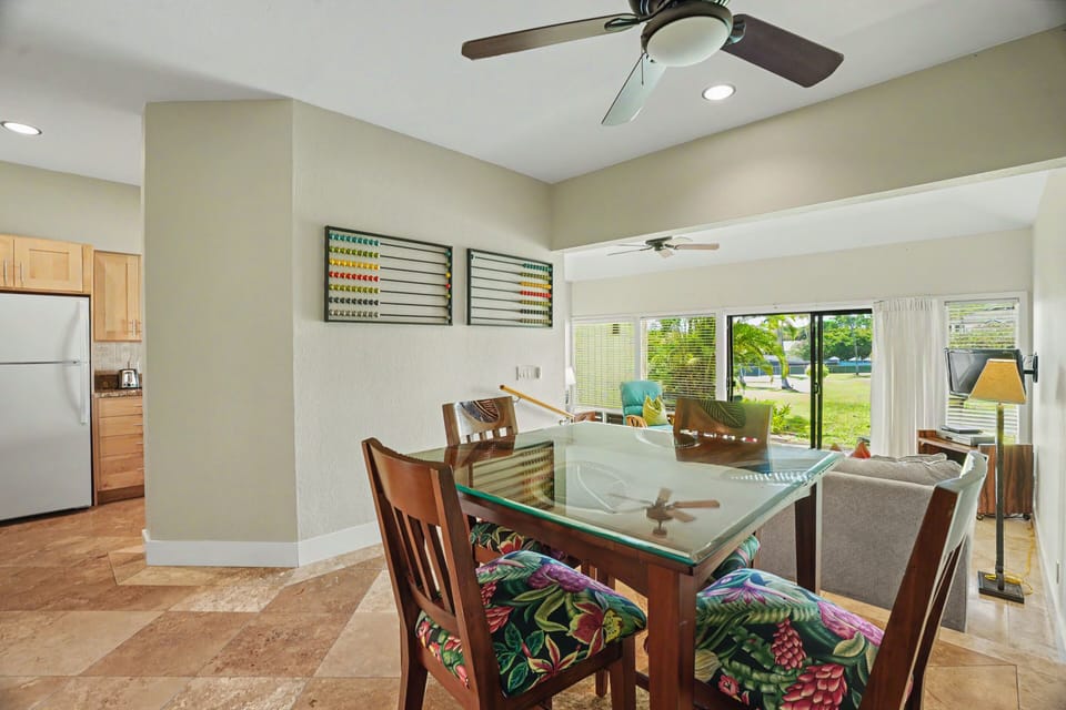 Your bright, open living and dining space features cheerful tropical accents, modern ceiling fans, and a sunny view of the yard—perfect for relaxing mornings and gathering with loved ones.