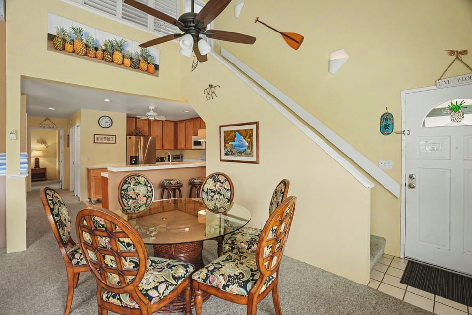 Gather around this inviting dining table beneath soaring vaulted ceilings, with a fully-equipped kitchen just steps away, perfect for preparing your favorite island-inspired meals together.