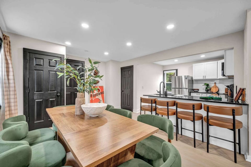 Open dining space w/ a wood table & green chairs, flowing right into the kitchen.