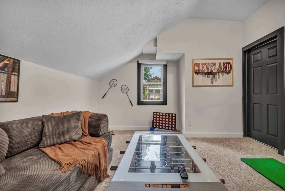 Cozy game room with a foosball table, Cleveland-themed wall décor, and a couch that converts into a pullout daybed