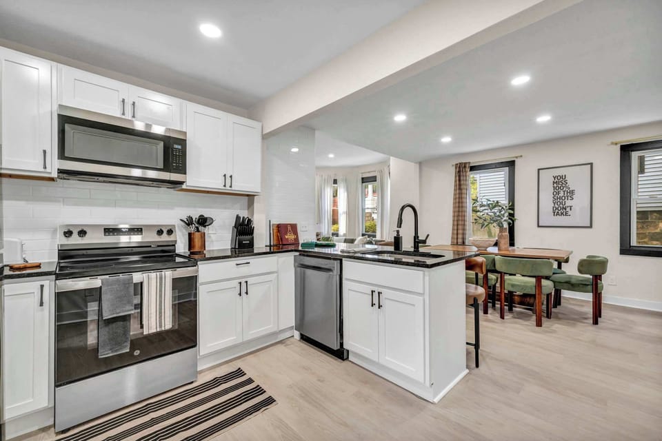 Sleek white kitchen w/ stainless steel appliances & a spacious island for cooking together.