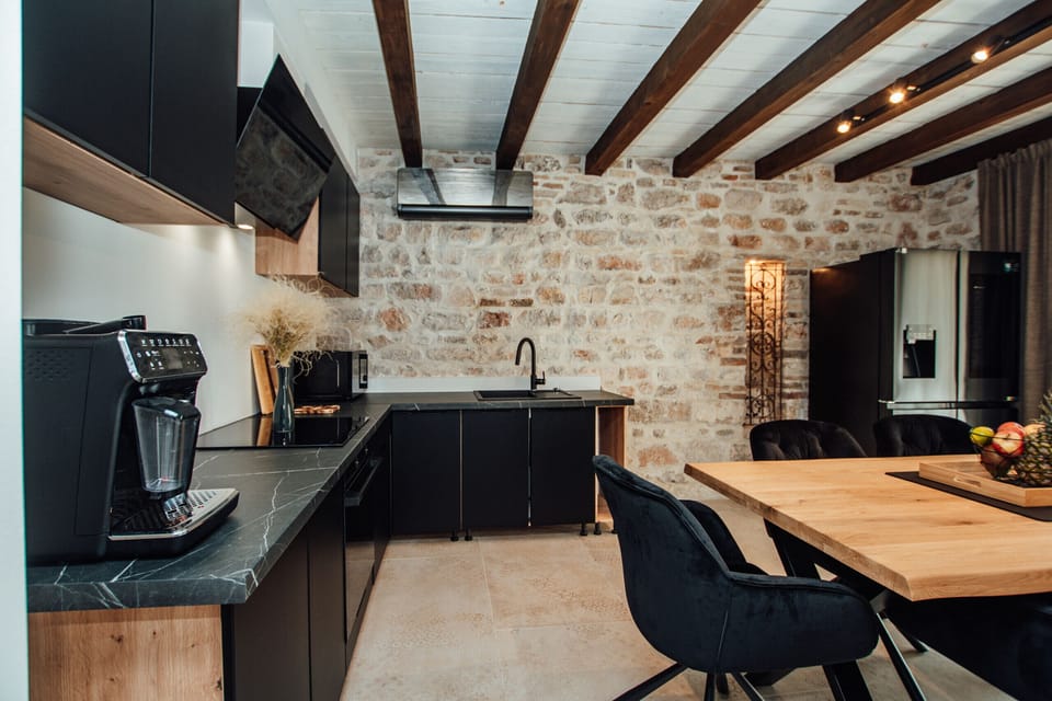Modern kitchen with dining area, stone wall, wooden beams and fully equipped kitchenette.
