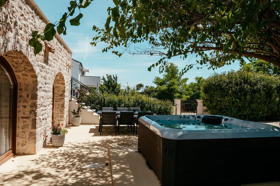 Private garden area with whirlpool, outdoor dining space and stone façade.