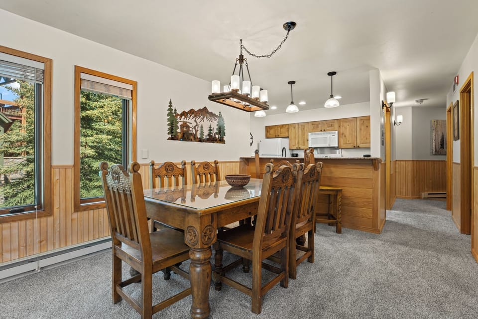 Gather around this inviting dining table where warm wood accents and mountain views create the perfect setting for your memorable meals together.