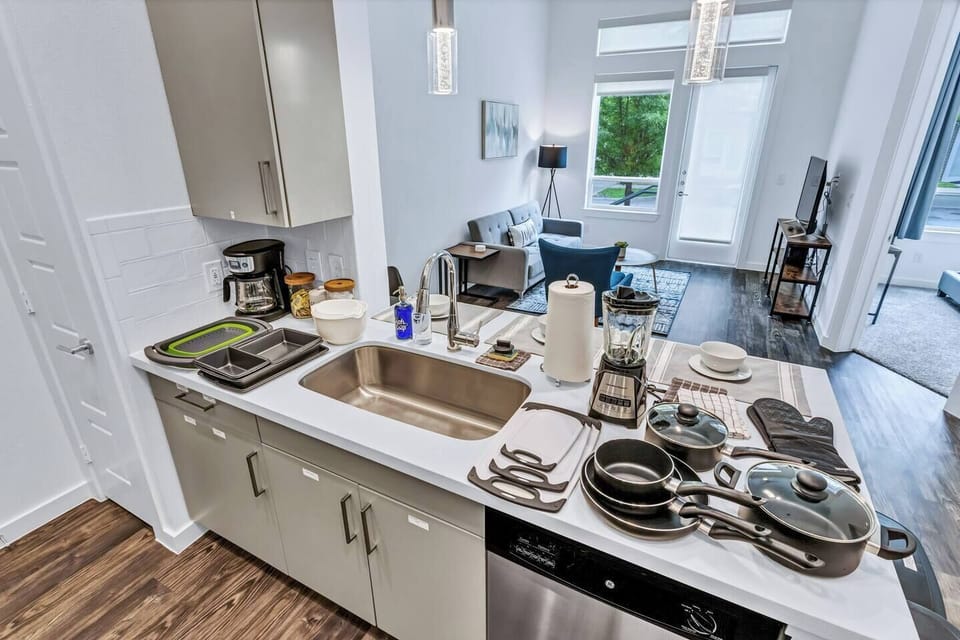 Fully equipped kitchen including a toaster, blender, mixing bowls, colander, cutting boards, pots and pans, kitchen mits and baking pans.