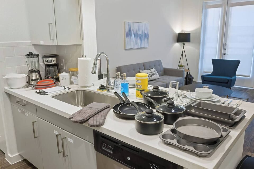 Fully equipped kitchen including a toaster, blender, mixing bowls, colander, cutting boards, pots and pans, kitchen mits and baking pans.