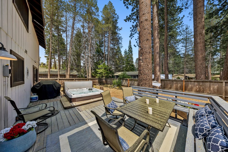 Outdoor deck featuring a metal dining table with cushioned chairs, built-in bench seating, and a stone-patterned rug.