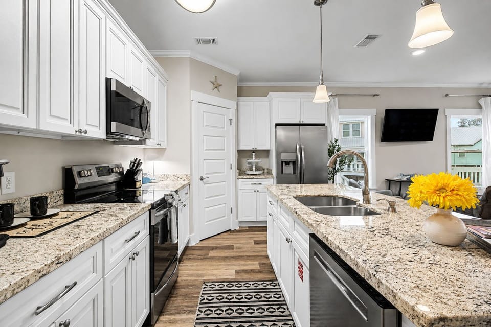 Kitchen from a second angle, showing white upper cabinets and contemporary pendant lighting above the counter