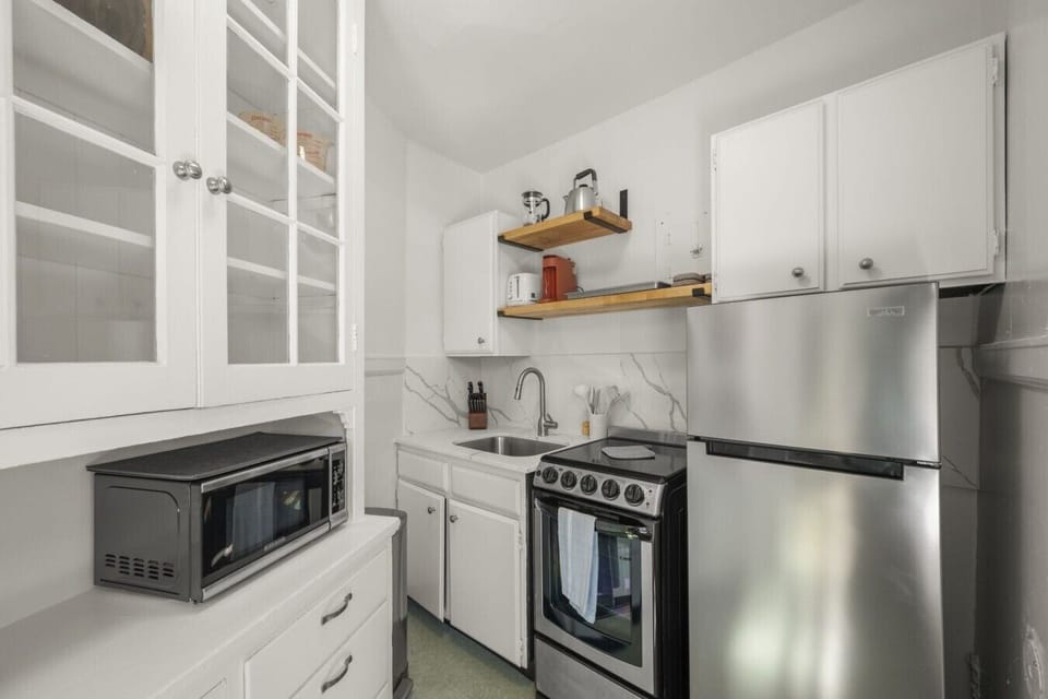 Compact yet functional kitchen with stainless steel appliances, cookware, dishes, and essentials for everyday cooking.