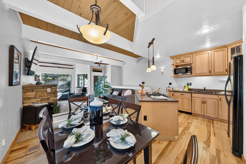The formal dining area features a dark wood table set beneath an elegant light fixture, adjacent to the open kitchen.