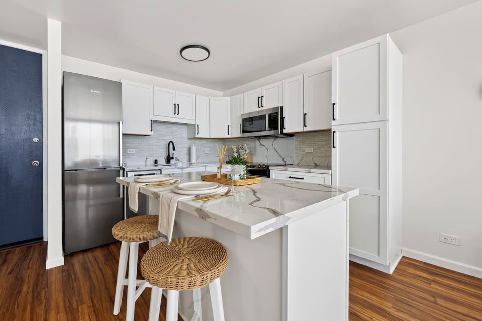The gourmet kitchen features an integrated breakfast bar, seating, and modern stainless steel appliances.