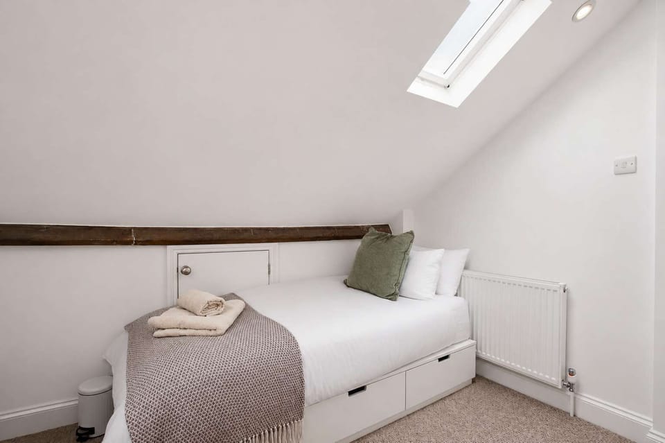 Attic Retreat: Cozy bed beneath rustic beams with clever storage and soft natural light!