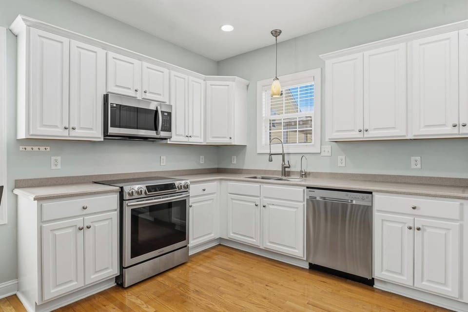Step into your fully equipped kitchen with sleek stainless steel appliances, abundant cabinetry, and warm wood floors—a bright, inviting space to prepare meals during your stay.