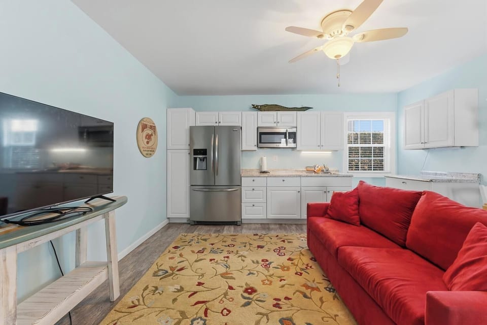 Relax in your bright living space with a plush sofa, flat-screen TV, and fully-equipped kitchen featuring stainless appliances and granite counters—perfect for cooking and unwinding.