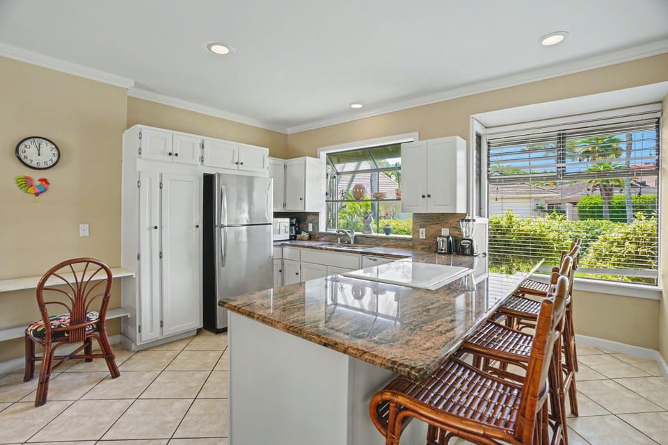 Step into your fully equipped kitchen with gleaming granite countertops, stainless steel appliances, and a bright window framing lush garden views—perfect for preparing meals in style.