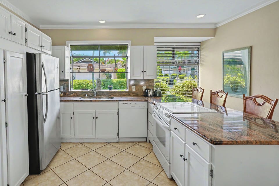 Prepare your favorite meals in this fully equipped kitchen with granite counters, stainless appliances, and a cozy island for dining or prepping while enjoying views of the neighborhood greenery.