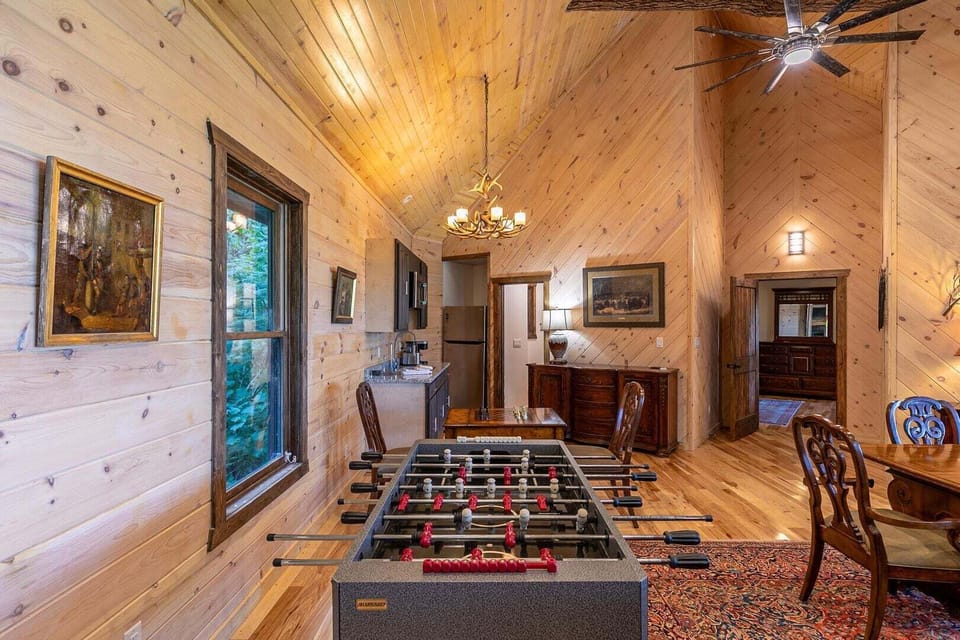 The wood-paneled game room is where the fun never stops — dramatic vaulted ceilings, warm wood character, and a foosball table that guarantees friendly competition and endless entertainment for the whole group.